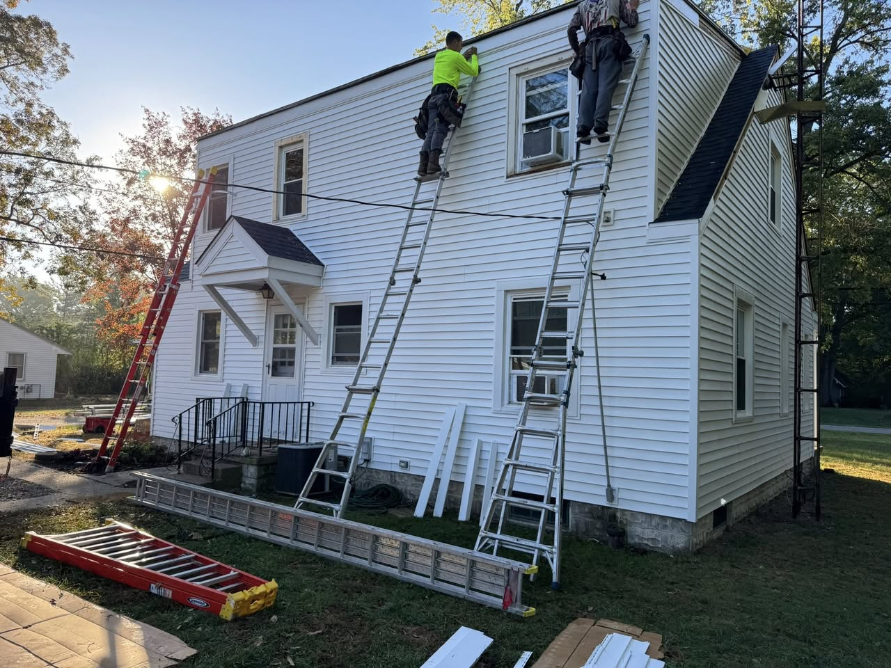 Siding installation — workers finishing siding at roofline